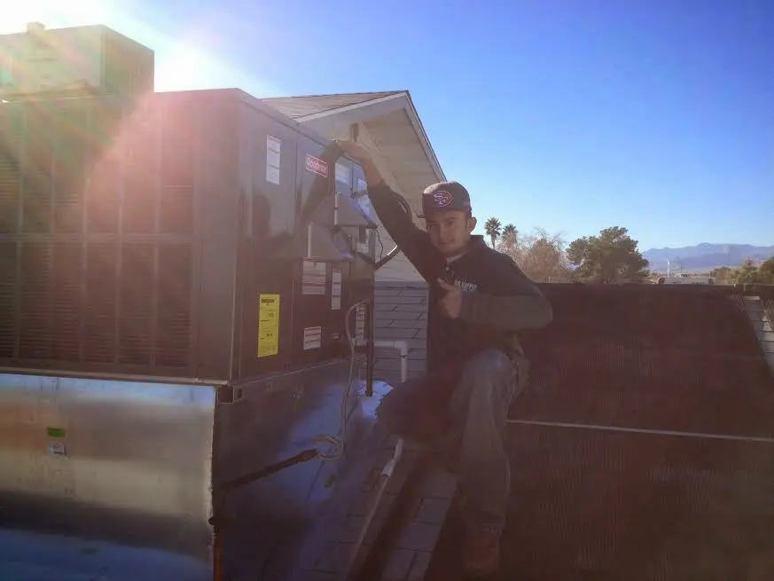 HVAC technician performing Air Duct Cleaning on a rooftop unit in Keyes